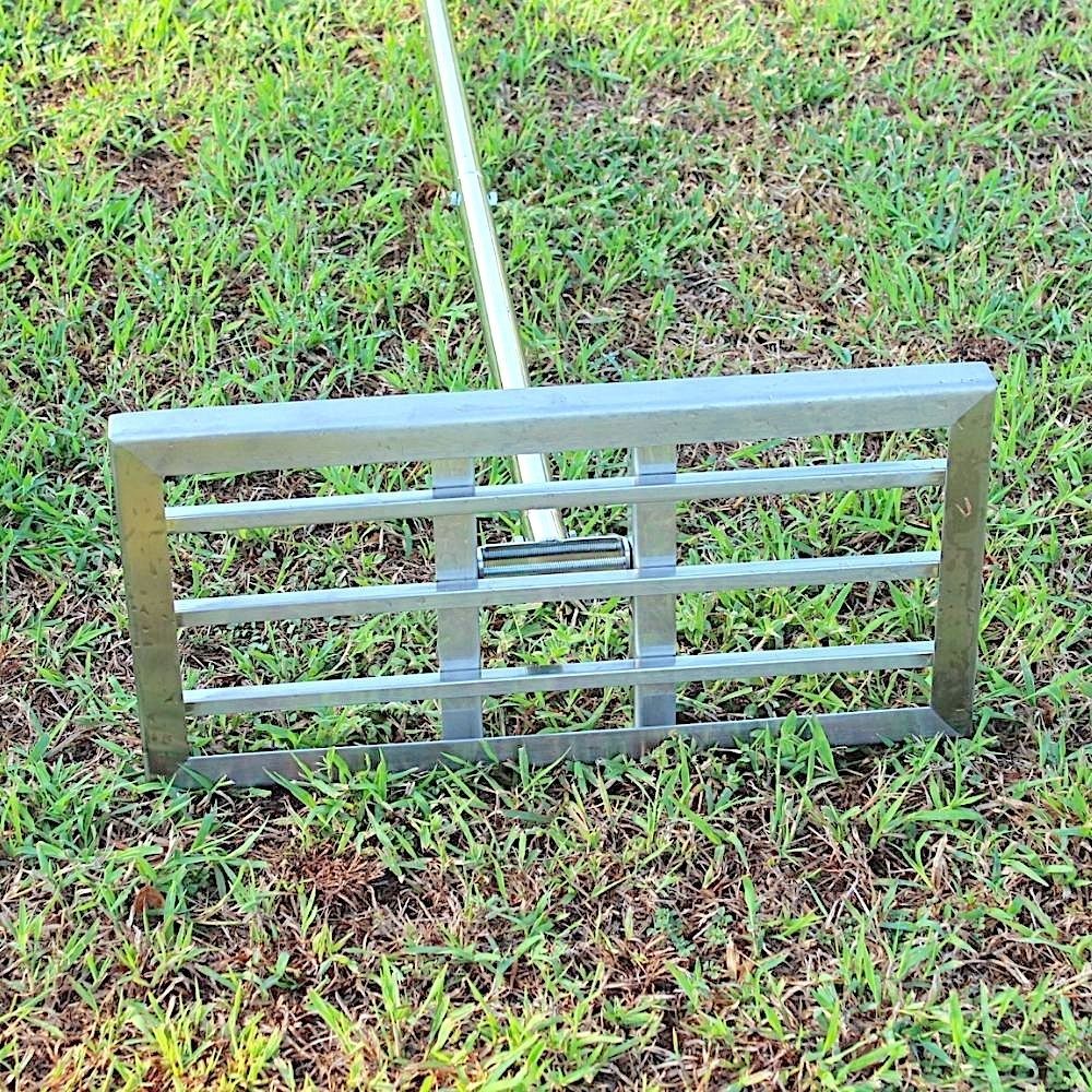 The stainless steel levelling rake grate standing on its edge on a lawn